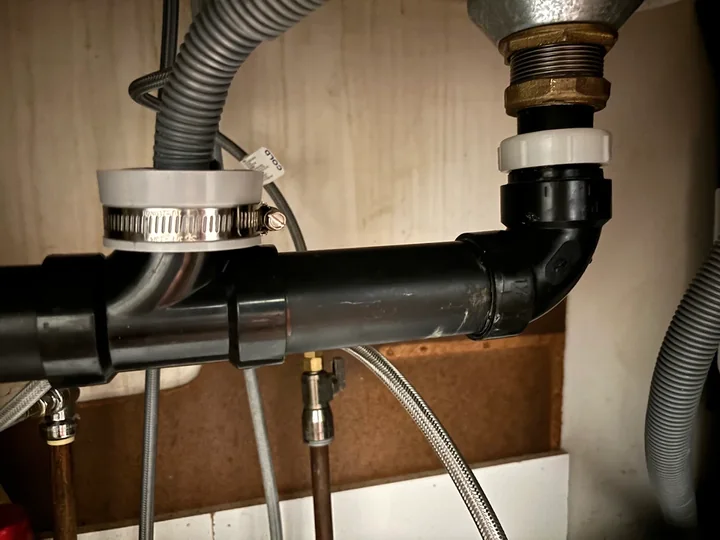 Kitchen sink drain pipes and hose connections inside a cabinet