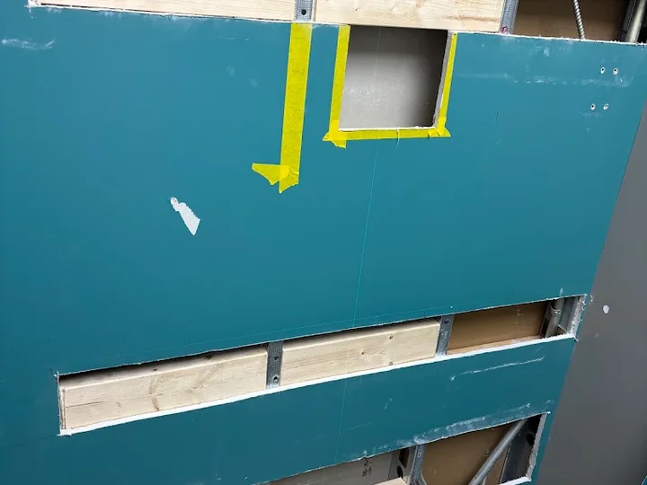 Open sections of a blue wall exposing timber backing during repair