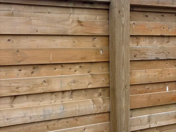 Horizontal wooden fence boards and a capped timber post